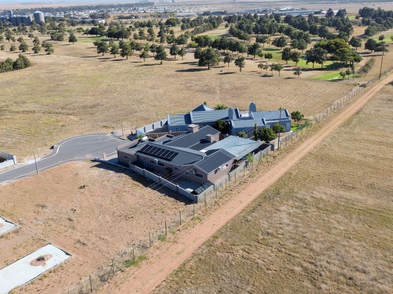 Aerial view of a residential property featuring a tiled roof with integrated solar panels, set within a spacious, open landscape.