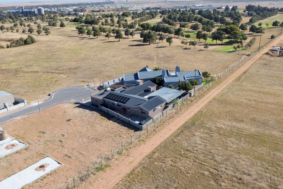 Aerial view of a residential property featuring a tiled roof with integrated solar panels, set within a spacious, open landscape.