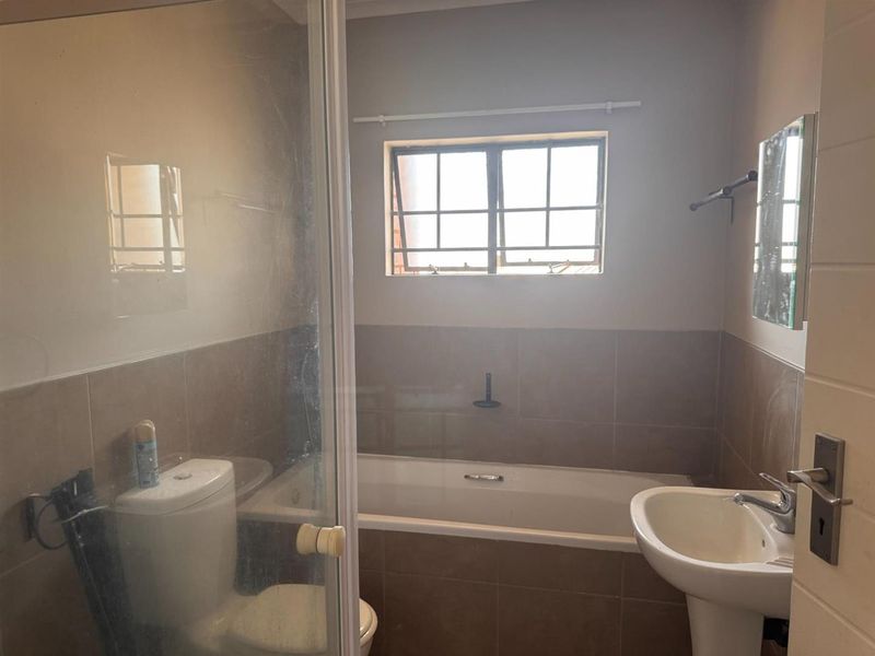 A functional bathroom featuring a bathtub, pedestal basin, toilet, and a separate shower enclosure with tiled finishes.