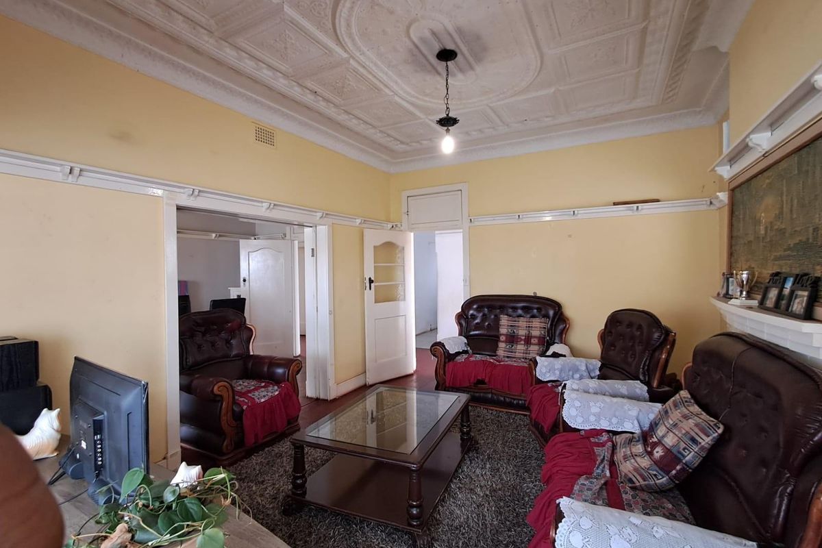 A traditional living room featuring a decorative pressed metal ceiling, picture rails, and original timber door frames, offering a classic architectural foundation.