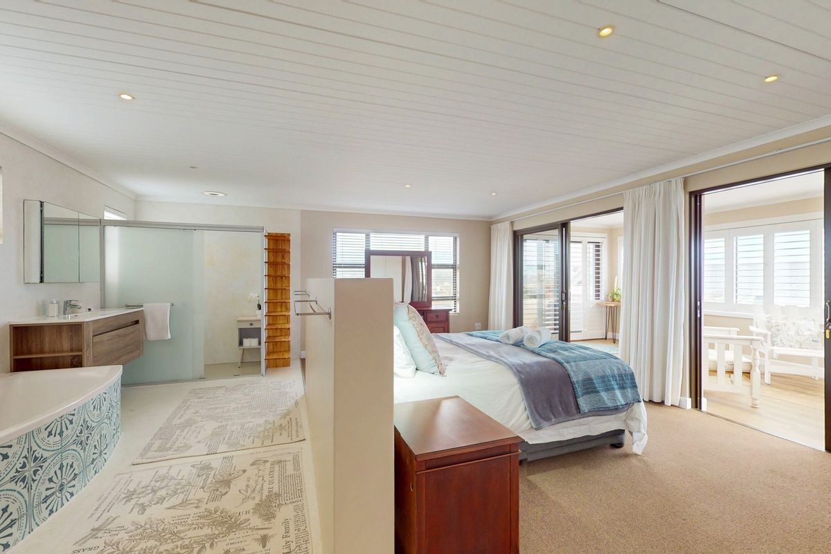 Spacious open-plan bedroom featuring an integrated en-suite bathroom with a soaking tub, glass-enclosed shower, and sliding door access to a private balcony.