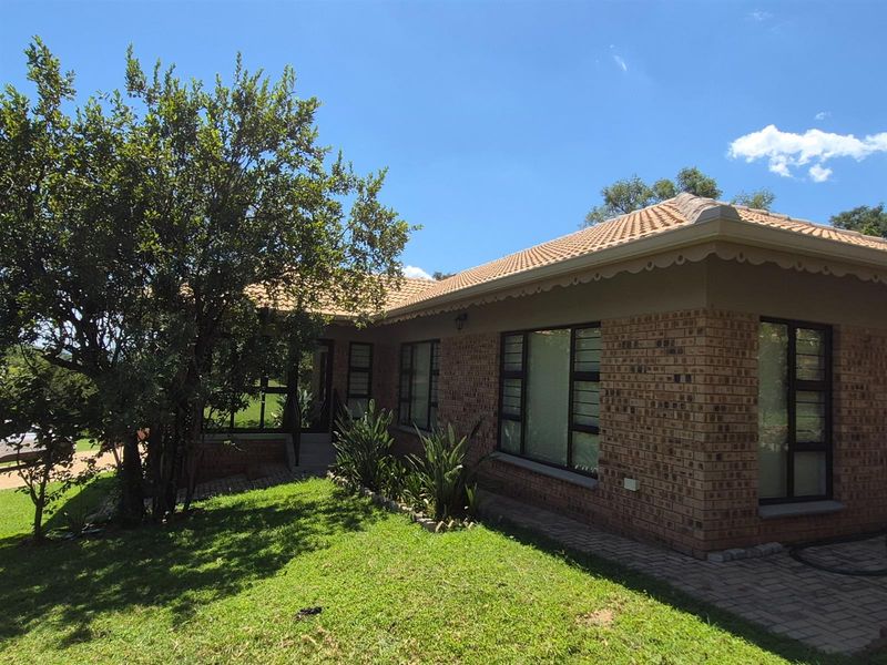 A view of the exterior front facade featuring face brick construction, a tiled roof, and large windows with security bars.