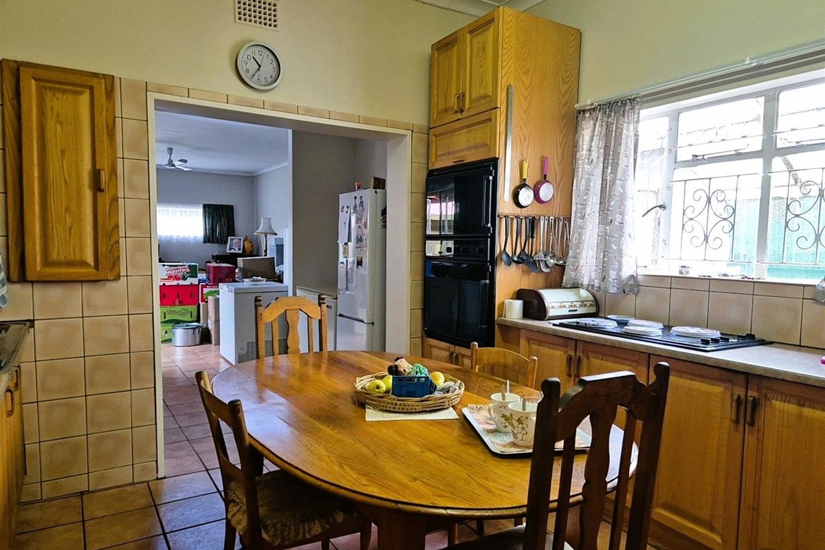 A functional kitchen featuring wooden cabinetry, built-in oven, and tiled flooring, with an open-plan layout leading into the adjacent living area.