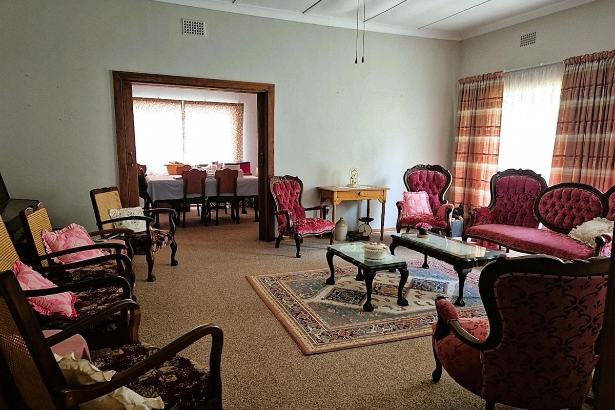 Spacious living room featuring carpeted flooring, large windows with curtains, and an open-plan transition into the adjacent dining area.