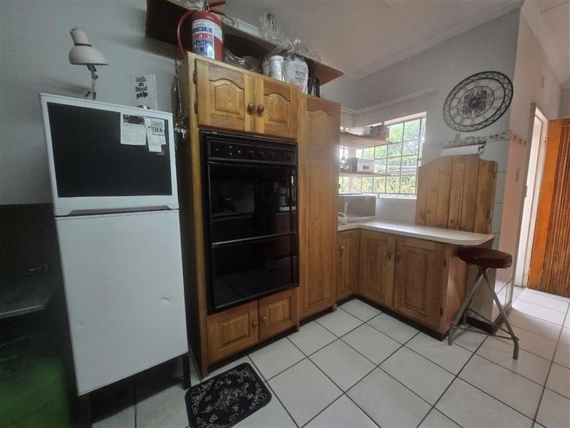 A dated kitchen featuring traditional wooden cabinetry, built-in oven, and tiled flooring, offering potential for a modern renovation to enhance functionality and aesthetic appeal.