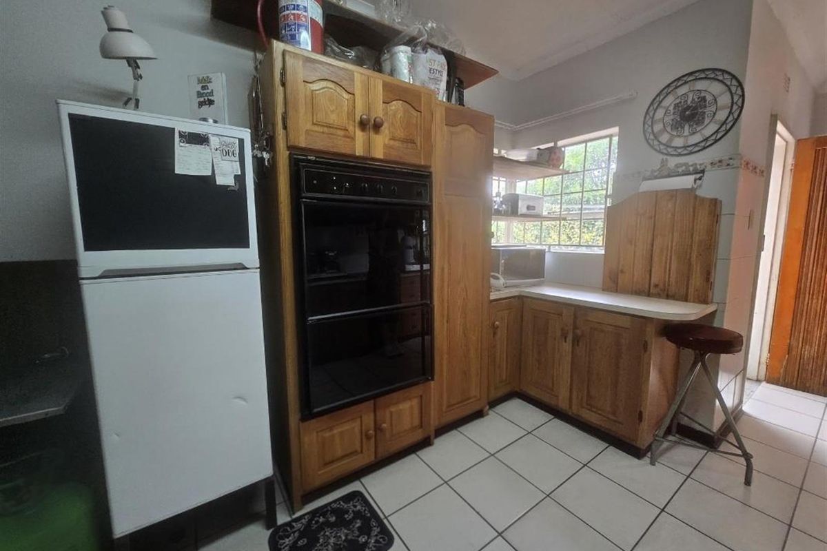 A dated kitchen featuring traditional wooden cabinetry, built-in oven, and tiled flooring, offering potential for a modern renovation to enhance functionality and aesthetic appeal.