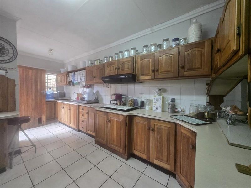 A functional kitchen featuring traditional wooden cabinetry, tiled flooring, and a tiled backsplash, offering a classic layout with ample storage space.