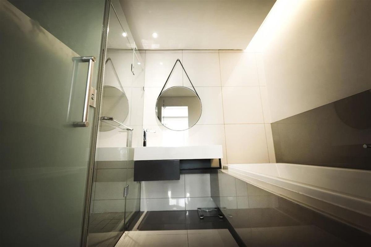 Modern bathroom featuring a sleek wall-mounted vanity, a glass-enclosed shower, and a built-in bathtub with contemporary tiling.