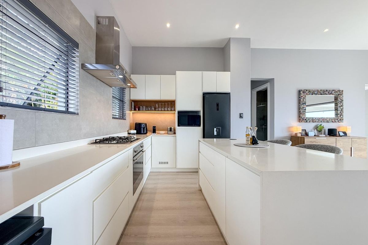 Modern, well-appointed kitchen featuring sleek white cabinetry, quartz countertops, integrated appliances, and a central island, creating a clean and functional culinary space.