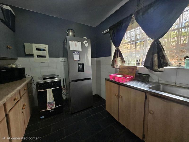 A functional kitchen featuring built-in wooden cabinetry, a stainless steel sink, tiled splashbacks, and a window with security bars.