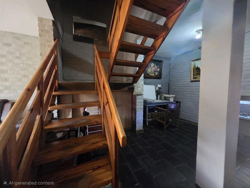 A hallway area featuring a timber staircase, slate tile flooring, and painted brick walls, offering a rustic aesthetic with potential for modernization.