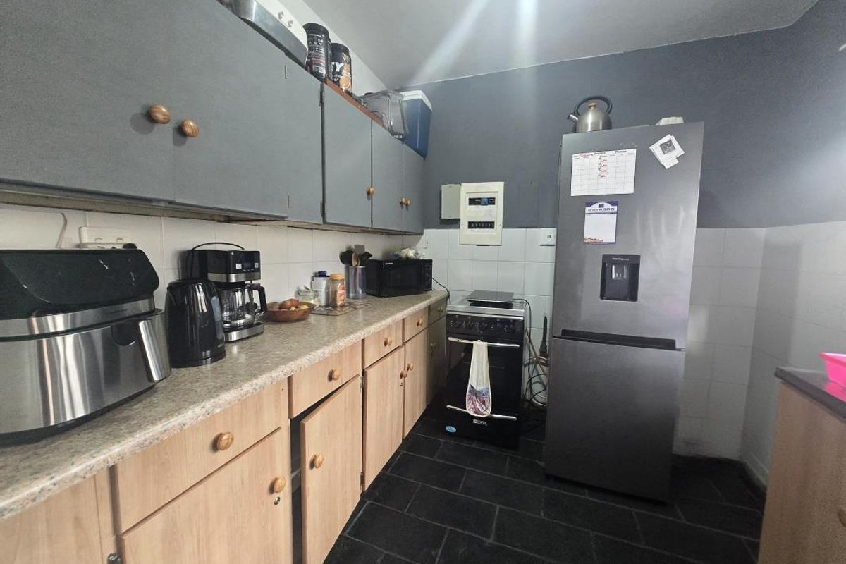 A functional kitchen featuring laminate countertops, tiled backsplash, and a mix of upper and lower cabinetry with a freestanding stove.