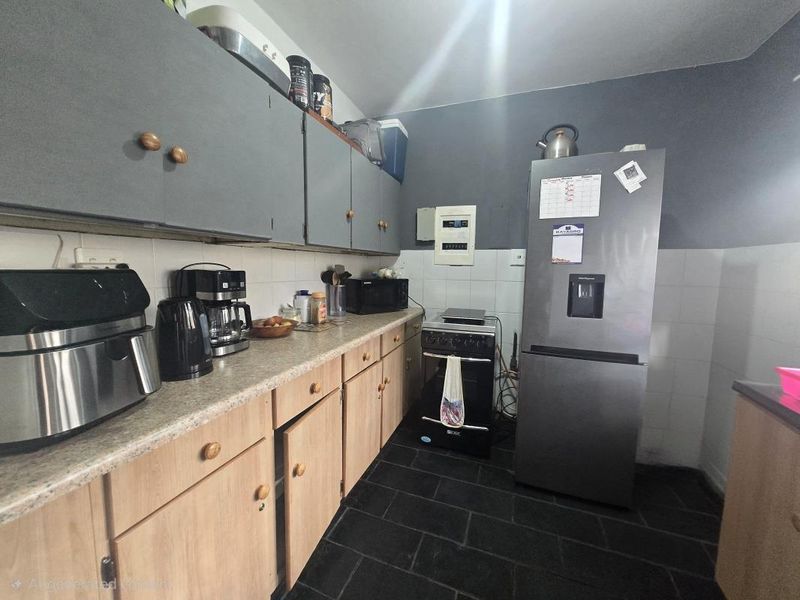 A functional kitchen featuring laminate countertops, tiled backsplash, and a mix of upper and lower cabinetry with a freestanding stove.