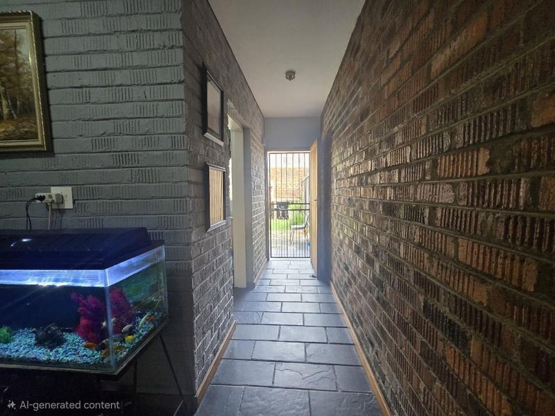 A hallway featuring exposed brick walls and stone tile flooring, leading to an exterior security gate.