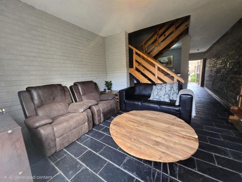 Living area featuring exposed brick walls, slate tile flooring, and a timber staircase leading to the upper level.
