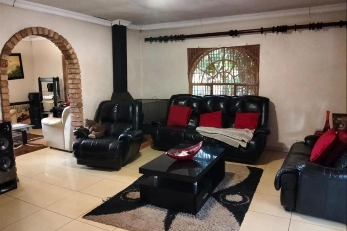 Spacious living room featuring a built-in fireplace, tiled flooring, and a distinctive brick archway leading to an adjacent area.