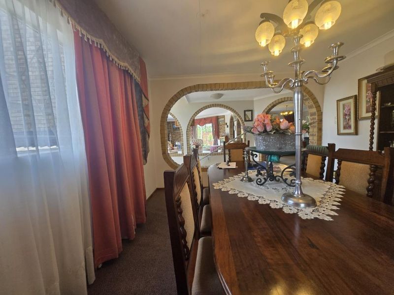 A traditional dining room featuring distinctive brick archways that connect to adjacent living spaces, finished with carpet flooring and classic coving.