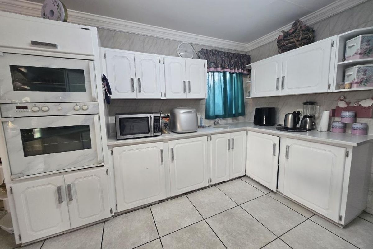 A functional kitchen featuring white cabinetry, built-in oven and microwave, tiled flooring, and a tiled backsplash.