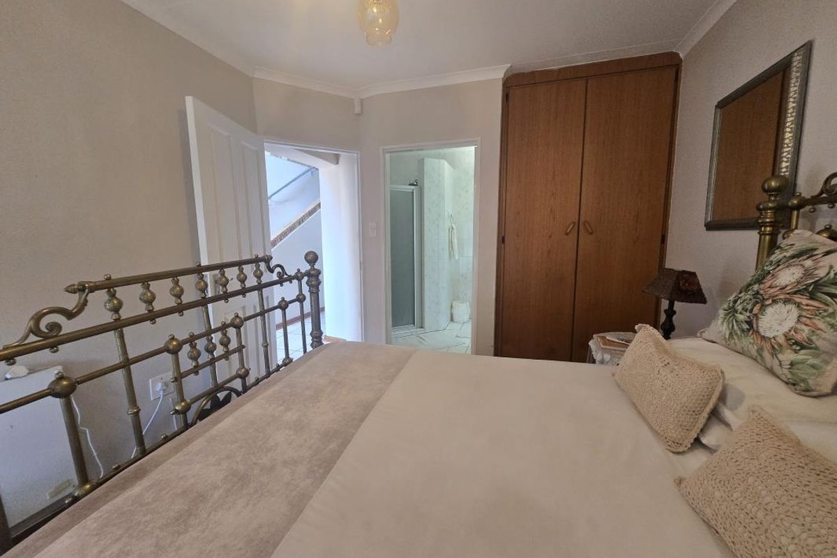 A bedroom featuring a built-in wooden wardrobe and direct access to an en-suite bathroom.