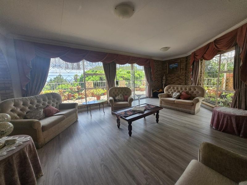Spacious living room featuring laminate flooring, exposed brick accents, and large sliding glass doors that provide ample natural light and access to the outdoors.