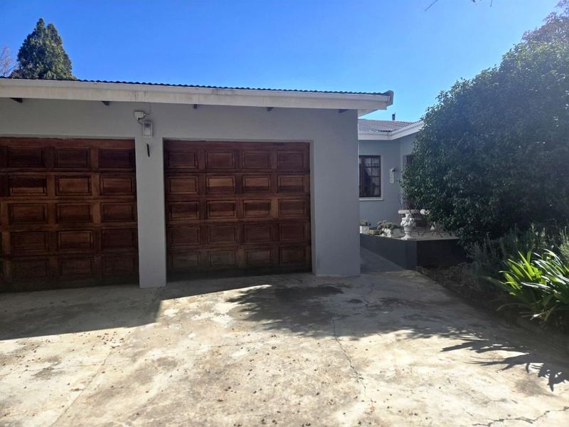 Front view of the property featuring a double garage with wooden doors and a concrete driveway.