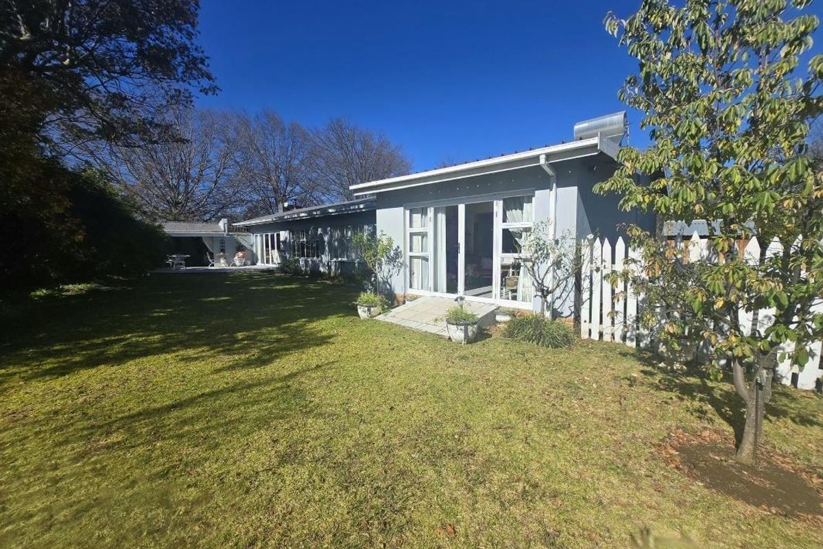Rear view of the property featuring a landscaped garden, concrete patio area, and sliding glass doors providing access to the home.