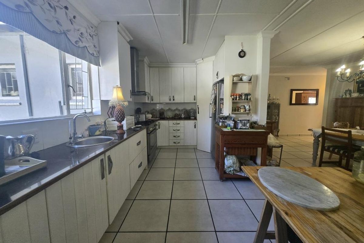 A functional kitchen featuring white cabinetry, tiled flooring, and a stainless steel sink, with an open-plan layout connecting to the dining area.