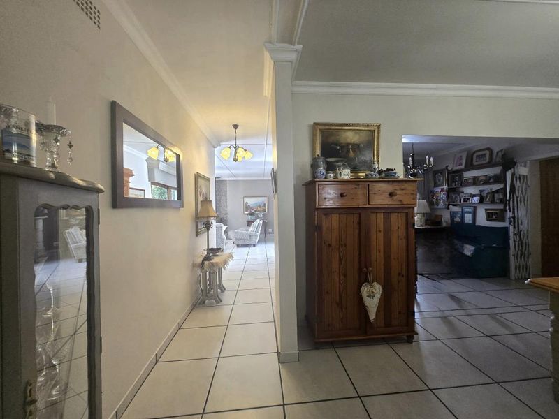 A spacious hallway featuring tiled flooring and crown molding, providing a central transition area connecting the living spaces of the home.