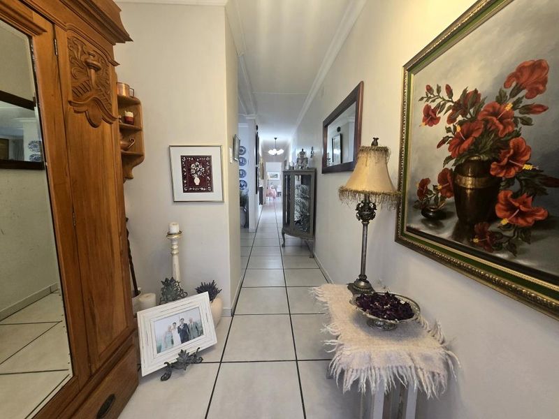 A long, tiled hallway providing access through the home, featuring neutral wall finishes and decorative coving.