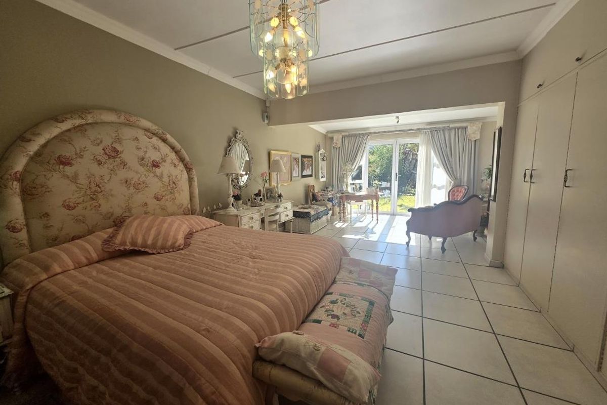 Spacious bedroom featuring tiled flooring, built-in cupboards, and glass sliding doors providing natural light and access to the outdoor area.