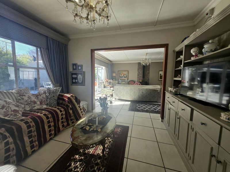 Spacious living area featuring tiled floors, built-in cabinetry, and a wood-burning fireplace, connecting to an adjacent lounge space with large windows.