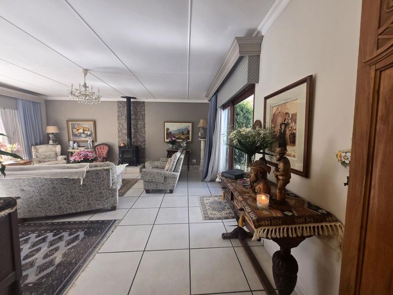 Spacious living room featuring a stone-clad wood-burning fireplace, large sliding glass doors for natural light, and neutral tiled flooring throughout.