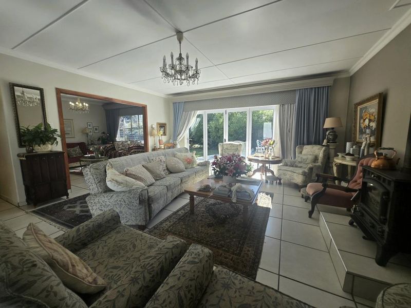 Spacious living room featuring tiled flooring, a fireplace, and large sliding glass doors that provide natural light and access to the garden.