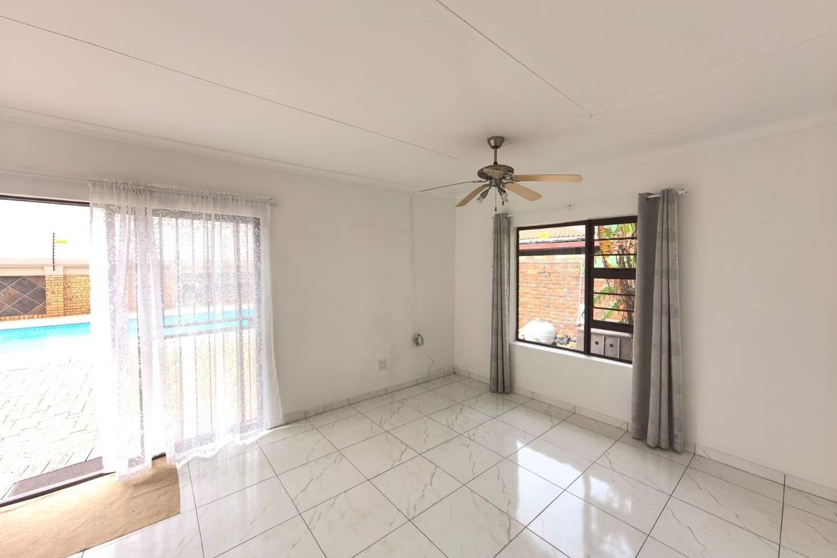 Bright living area featuring modern marble-look floor tiles, a ceiling fan, and sliding glass doors providing direct access to the pool area.