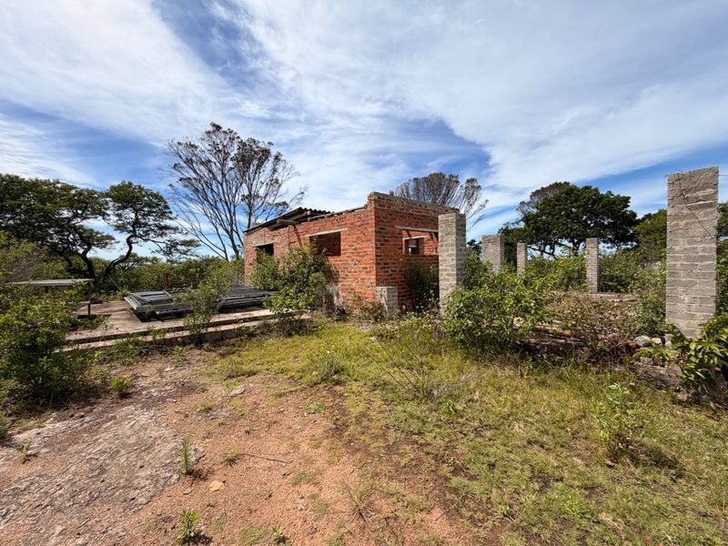 A derelict farm building structure featuring exposed brick walls and concrete columns, currently in a state of significant disrepair and requiring complete renovation.