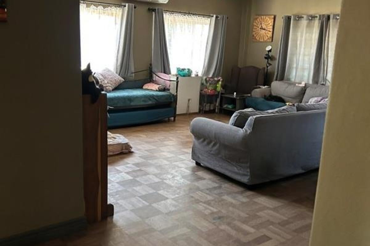 A spacious living room featuring classic parquet flooring and a wall-mounted split-system air conditioner, offering a comfortable and functional living space.