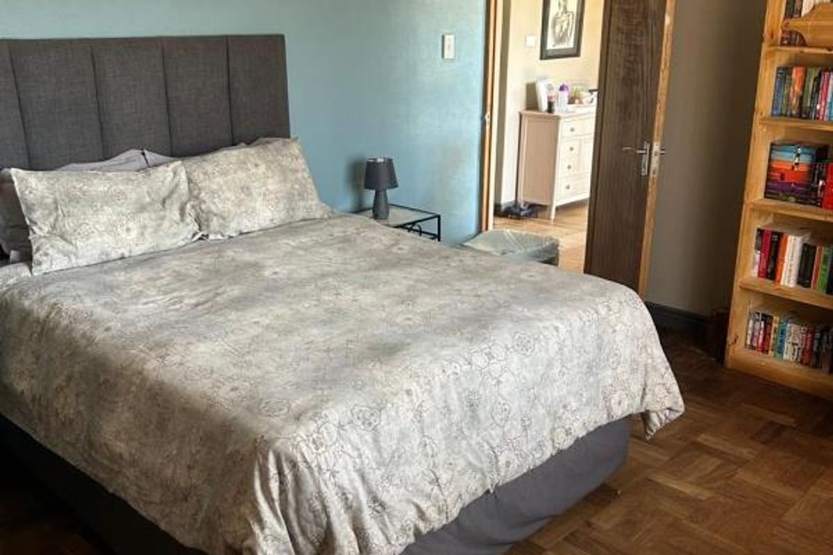 A bedroom featuring classic parquet flooring, a blue accent wall, and traditional coving, providing a warm and functional living space.