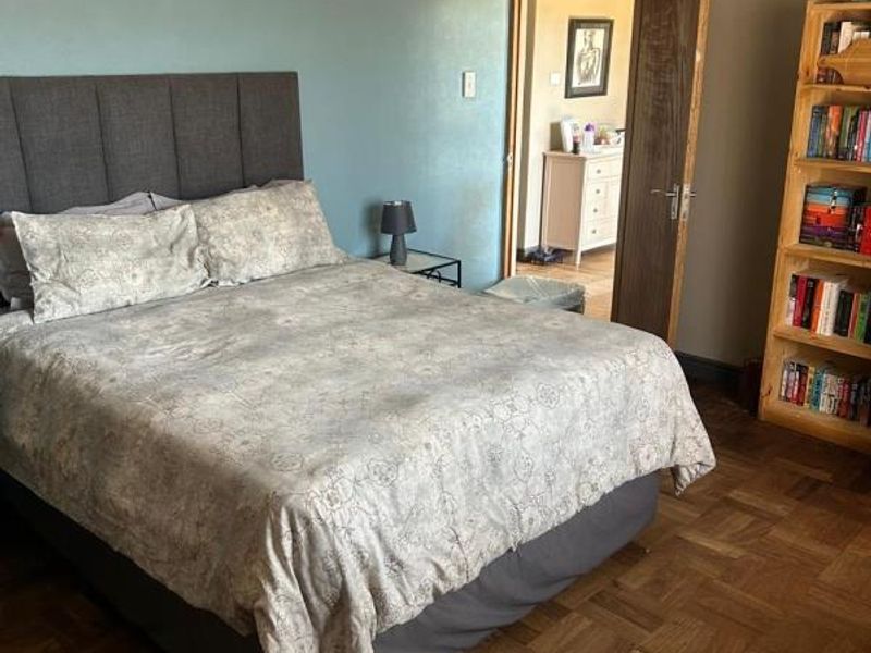 A bedroom featuring classic parquet flooring, a blue accent wall, and traditional coving, providing a warm and functional living space.