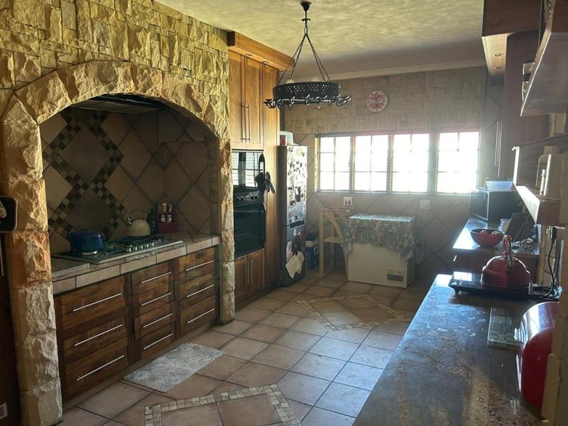 A rustic kitchen featuring a prominent stone archway over the cooking area, wooden cabinetry, and tiled flooring with a traditional design.
