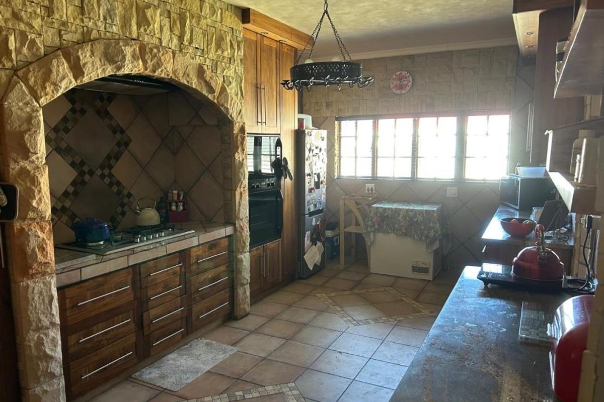 A rustic kitchen featuring a prominent stone archway over the cooking area, wooden cabinetry, and tiled flooring with a traditional design.