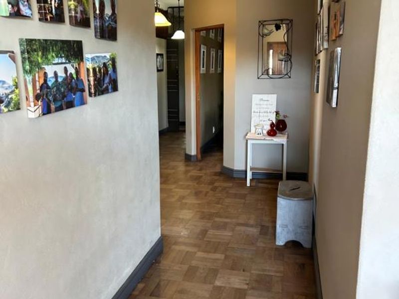A well-maintained hallway featuring classic parquet timber flooring, neutral wall tones, and decorative coving throughout the transition space.