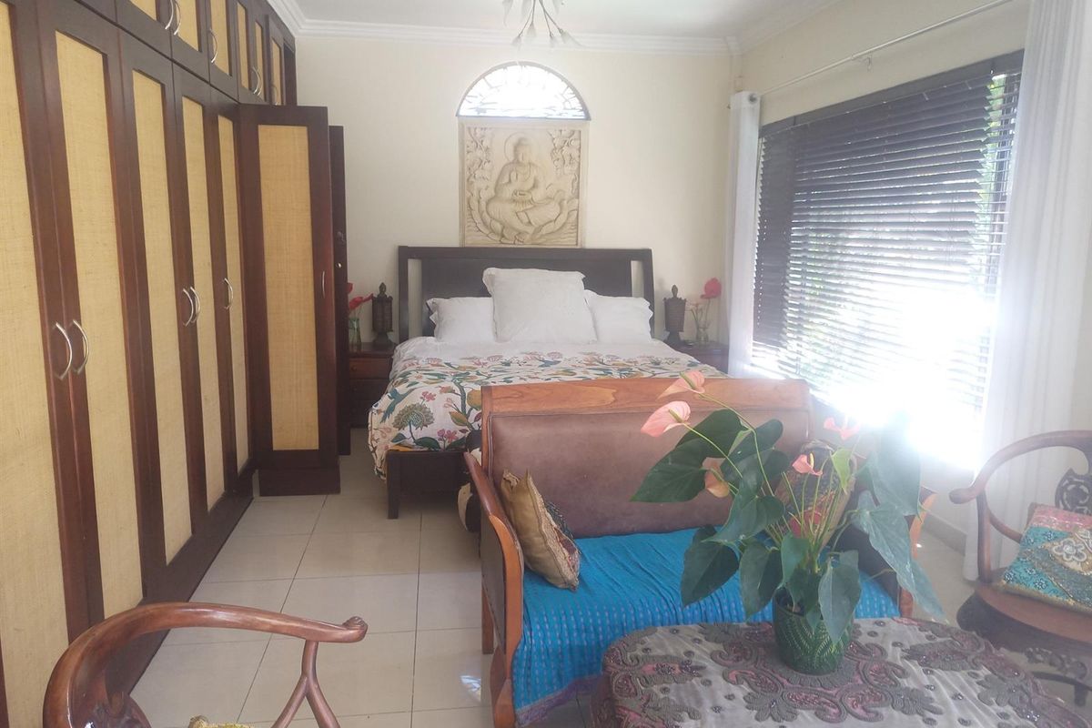 Spacious bedroom featuring extensive built-in cabinetry, tiled flooring, and natural light through venetian blinds.
