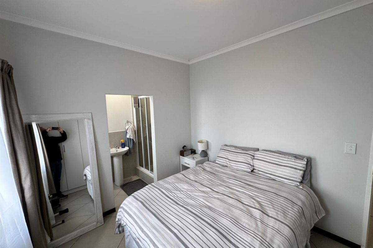 A bedroom featuring tiled flooring and an en-suite bathroom equipped with a pedestal basin and shower cubicle.