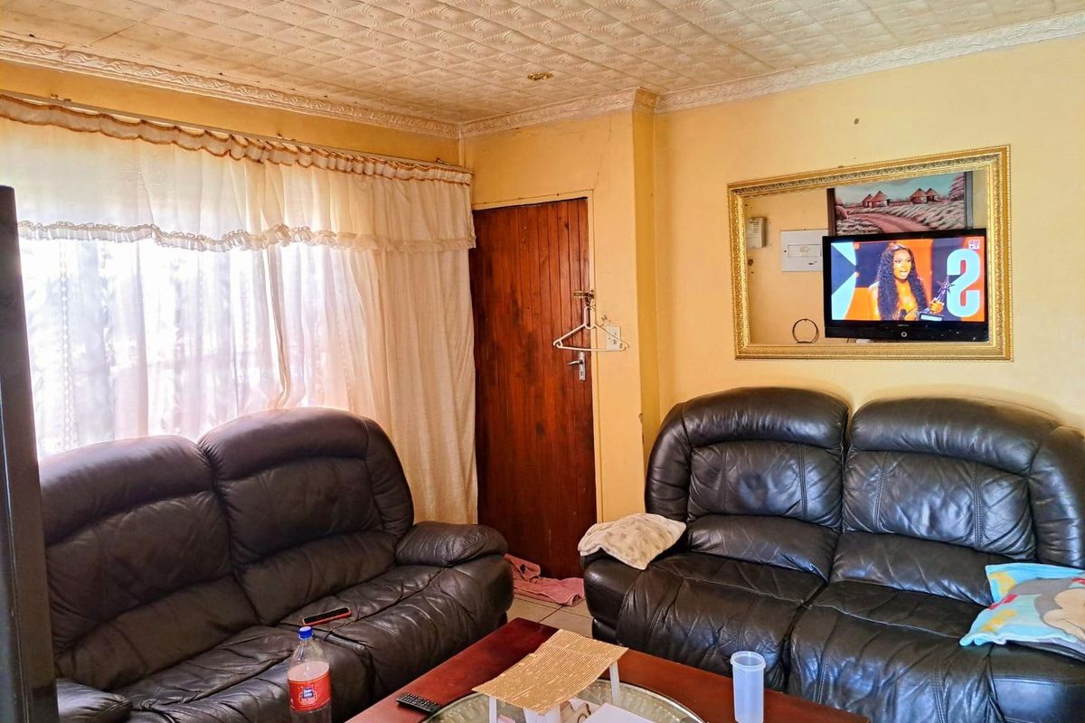 A living room featuring a textured ceiling, wooden door, and wall-mounted television, providing a functional space for relaxation.