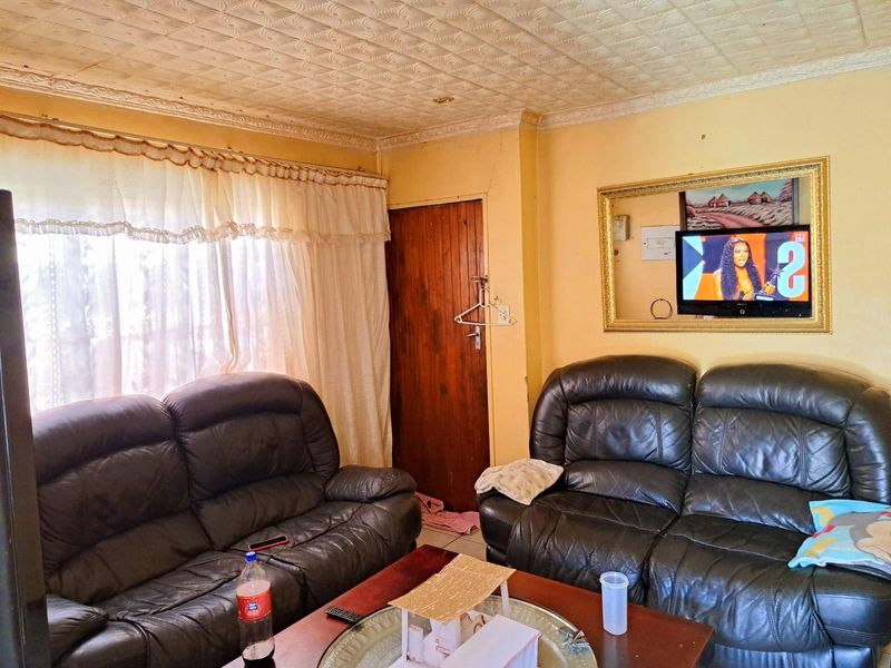 A living room featuring a textured ceiling, wooden door, and wall-mounted television, providing a functional space for relaxation.