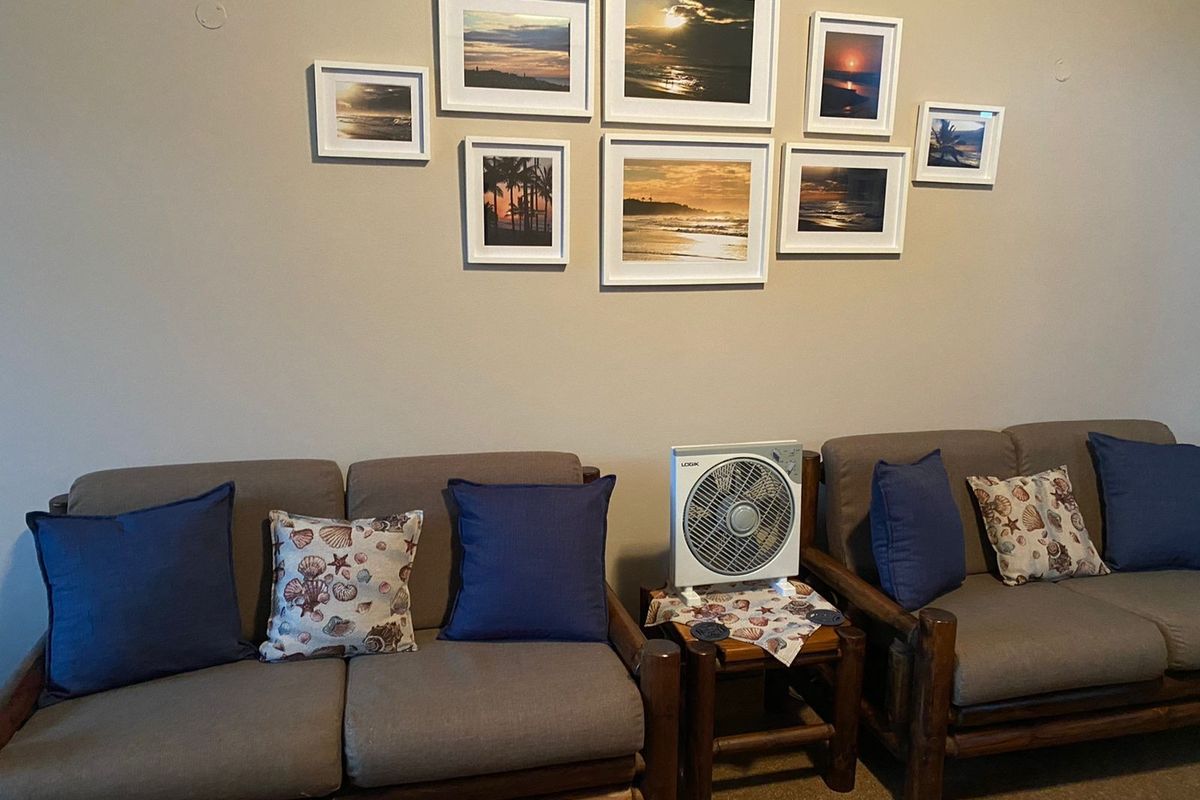 A living room area featuring a neutral wall backdrop with a gallery arrangement of framed coastal-themed artwork.