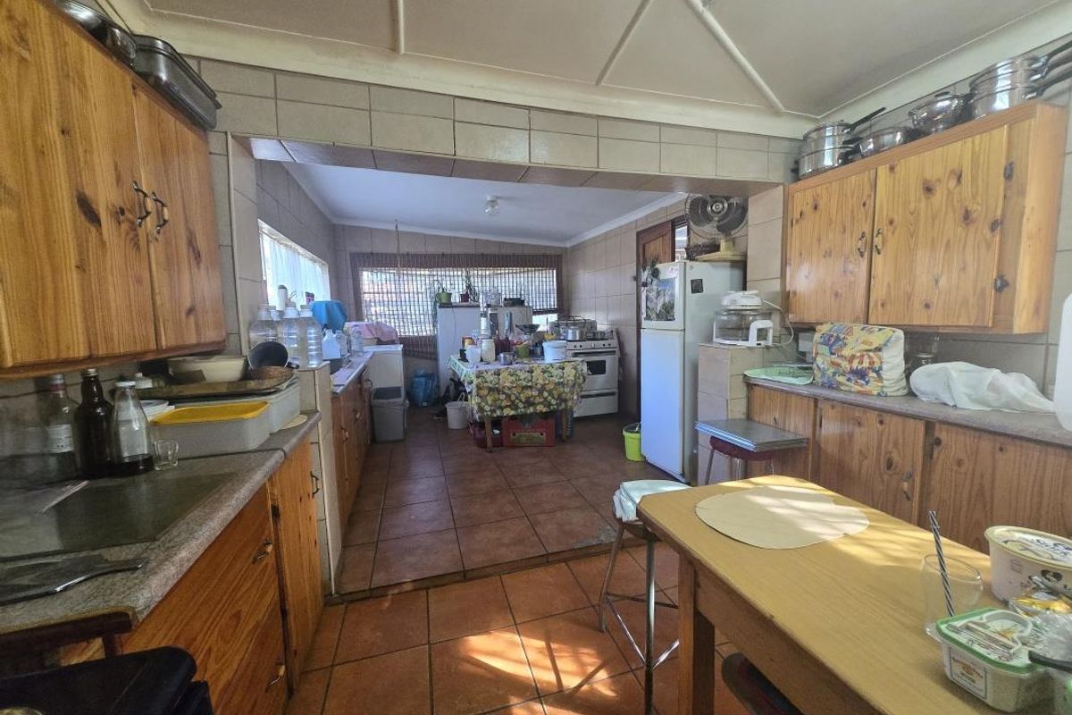 A functional kitchen featuring wooden cabinetry, tiled flooring, and a freestanding stove, offering a traditional layout with potential for modern updates.