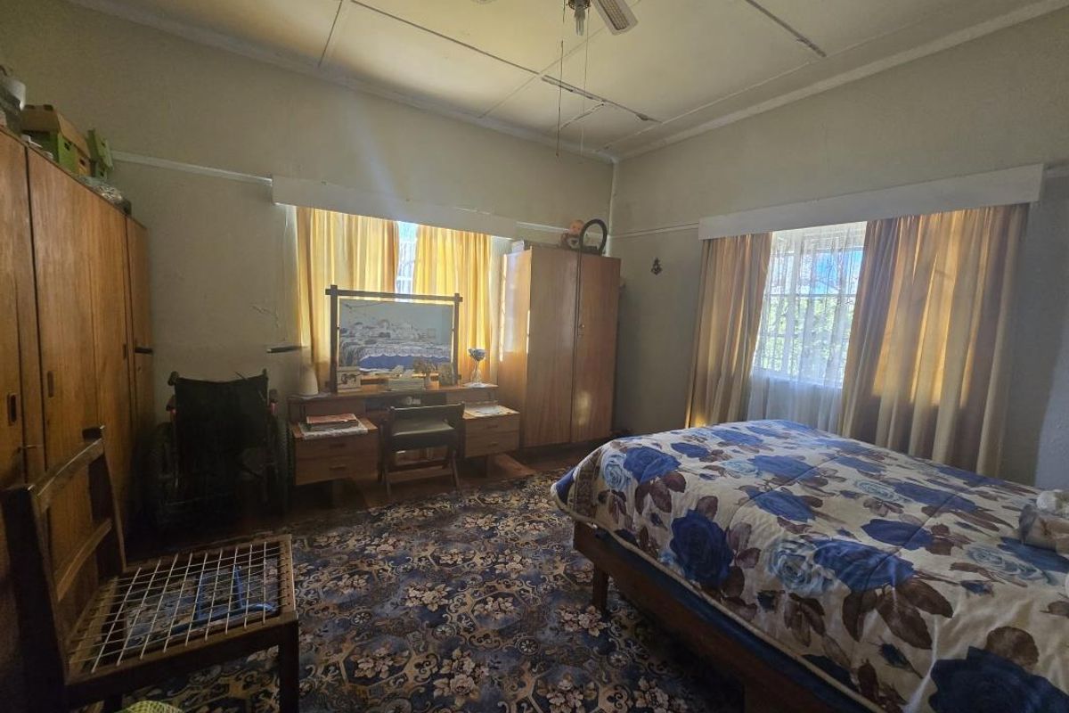 A bedroom featuring built-in cupboards and a ceiling fan, requiring cosmetic updates to modernize the space.
