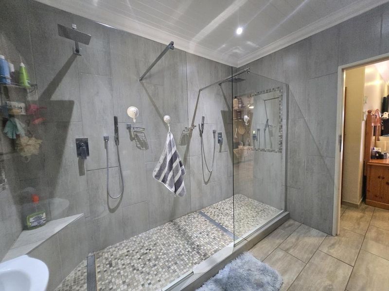 Modern bathroom featuring a spacious walk-in shower with dual shower heads, glass enclosure, and contemporary grey tiling.