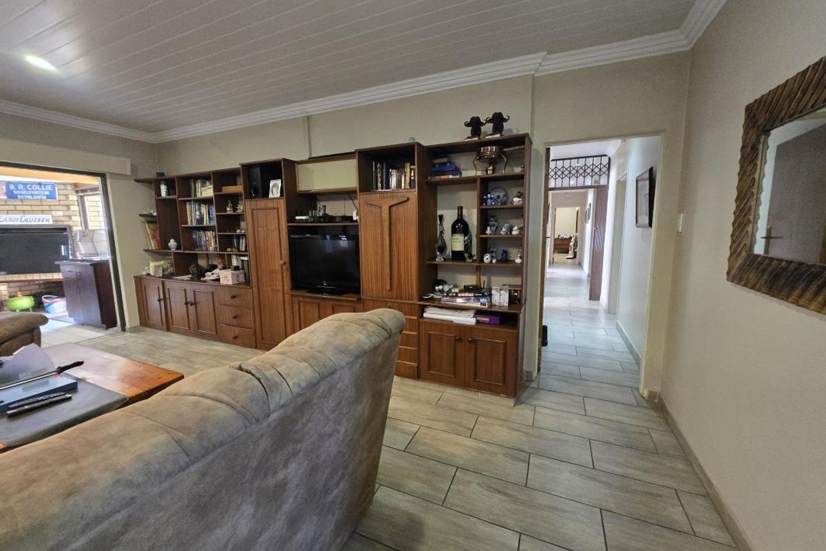 Living room featuring built-in wooden cabinetry, tiled flooring, and a tongue and groove ceiling with crown molding.